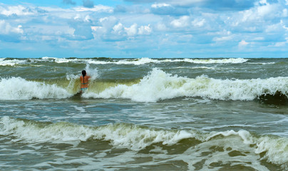 Swim during a storm at sea. Girl bathes in the sea waves.