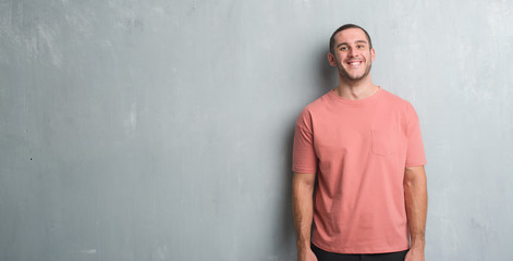 Young caucasian man over grey grunge wall with a happy and cool smile on face. Lucky person.