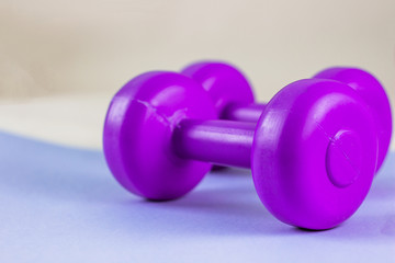 Brightly pink dumbbells on a lilac background. Healthy lifestyle, the concept of losing body weight. Cares about the body. Empty place for text.