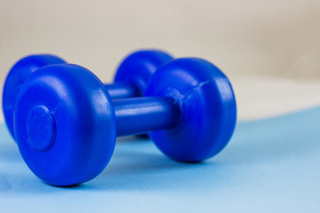 Obraz na płótnie Canvas Bright blue dumbbells on a blue background. Healthy lifestyle, the concept of losing body weight. Cares about the body. Empty place for text.