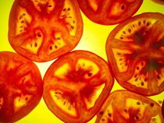 The sliced red tomato lies on a yellow glowing plate.