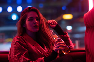 Long hair girl with sunglasses and leather jacket looking at neon lights