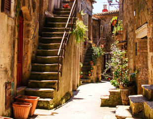 Obraz premium Stary dziedziniec w Pitigliano z wazami z kwiatami i ze schodami.