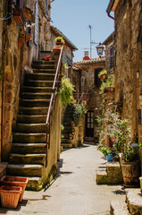 Old courtyard in Pitigliano with vases with flowers  and with stairs