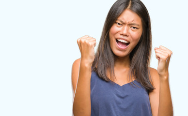 Fototapeta premium Young asian woman over isolated background very happy and excited doing winner gesture with arms raised, smiling and screaming for success. Celebration concept.