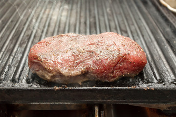 Sizzling raw beef steak on a grill