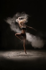 Slim woman dancing in white powder cloud