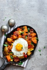 Skillet Breakfast Hash with potatoes bacon  peppers sweet potatoes and fried egg, top view