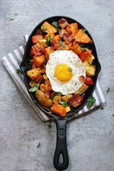 Skillet Breakfast Hash with potatoes bacon  peppers sweet potatoes and fried egg, top view