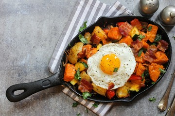Skillet Breakfast Hash with potatoes bacon  peppers sweet potatoes and fried egg, top view