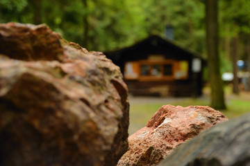 Detail of iron ore stone with wooden cottage on background in forest of Pressnitz river valley near Steinbach village in german Ore mountains during rain on 1st september 2018