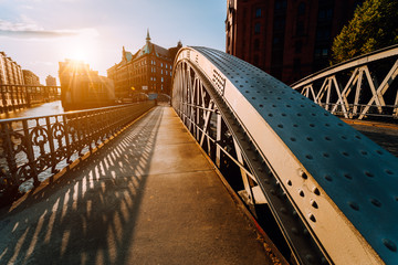 Metal arch bridge with rivets in the Speicherstadt of Hamburg during sunset golden hour with...