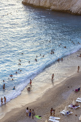 Vertical shoot of people enjoying on the cost of the beach at sunset time