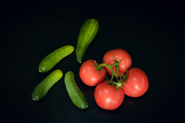   Tomatoes and cucumbers on black wood