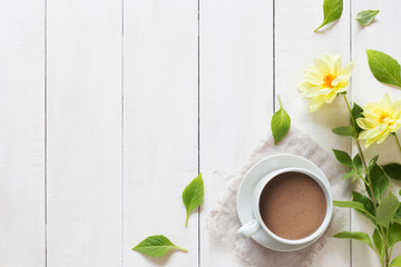 Cup of hot chocolate with flowers on wooden background