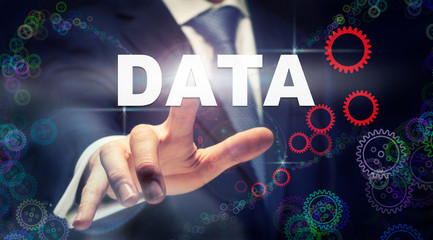 A businessman pressing a Data business concept on a graphical display of cogs