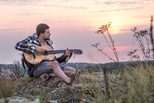 Guy with guitar play songs at sunny nature