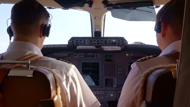 Two Caucasian experienced pilots in the cockpit or on the flight deck of modern aircraft piloting a private compact turboprop aircraft