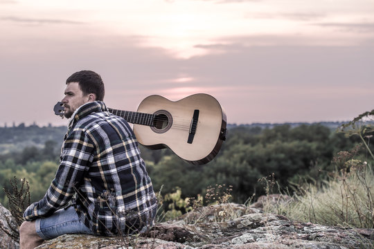 Guy with guitar play songs at sunny nature