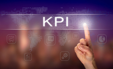 A hand selecting a KPI business concept on a clear screen with a colorful blurred background.
