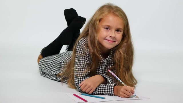 Studio shot girl on the floor drawing with pencils.