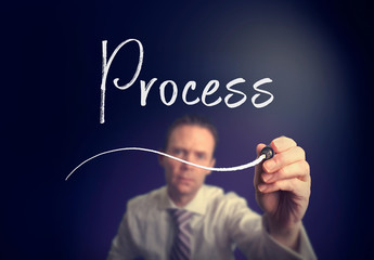 A businessman writing a process concept with a white pen on a clear screen.