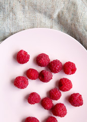 Raspberry on a pink plate on cloth, top view. Flat lay, overhead, from above.