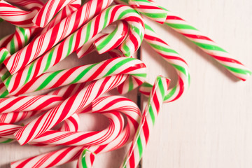 Lots of candy canes scattered on white rustic wooden desk. Chtistmas theme.