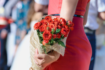 Red wedding bouquet of roses in hands on a background of red silhouette