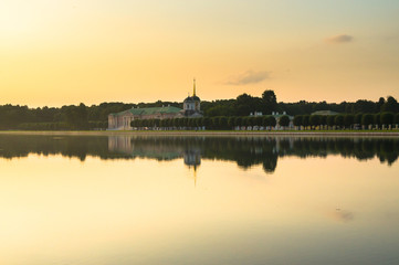 Fototapeta na wymiar Summer sunset on the palace pond of museum-estate Kuskovo, Moscow. Russia. Mysterious moment when the orange sun says goodbye to nature. Its last reflection trembles on the water. 