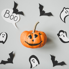 Happy halloween. Funny halloween pumpkin with paper bats and ghosts on gray background