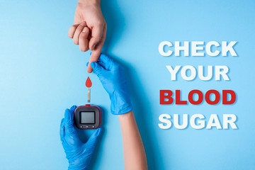 inscription check your blood sugar and Nurse making a blood test. Man's hand with red blood drop and Glucose meter