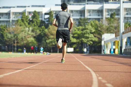 young asian male athlete running on track