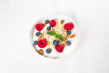 Gesundes Müsli mit Haferflocken, Joghurt, Himbeeren, Blaubeeren und Mandeln