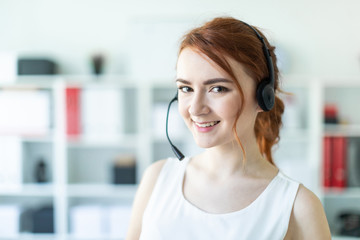 Naklejka premium Beautiful young girl in headphones with microphone standing in office.