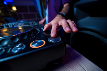 the man's hand with the clock presses the button of the DJ keypad