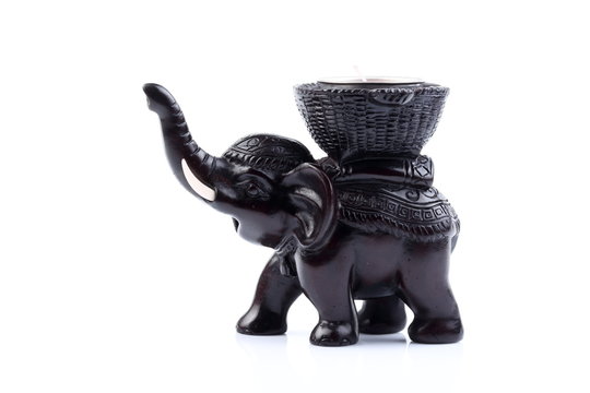 Black elephant made of resin like wooden carving with candle holder with white ivory. Stand on white background, Isolated, Art Model Thai Crafts, For decoration Like in the spa. Engraved pattern.