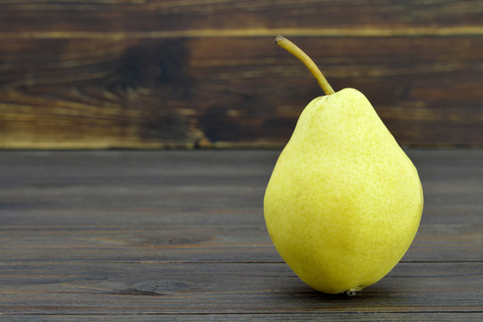 Ripe yellow pear on wooden background