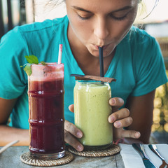 Woman is tasting different healthy drinks in vegan cafe