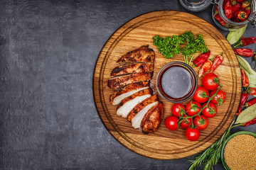 whole and sliced chicken breast with spices on a stone board, top view copy