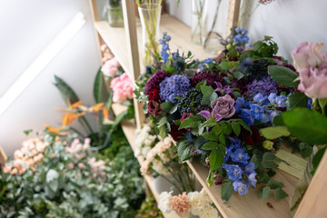 Flower shop concept. Different varieties fresh spring flowers in refrigerator room for flowers. Bouquets on shelf, florist business.