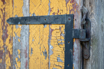 An old hinge mounted in the door. Old carpentry structures.