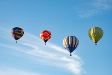 Four hot air balloons lined up in the sky