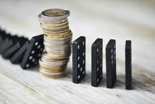 Strong currency or economy concept with pile of coins stopping the fall of black domino blocks
