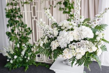 Wedding decoration, ceremony in a light tent. Gorgeous bouquet of different flowers. White floral arrangement in vintage vase.