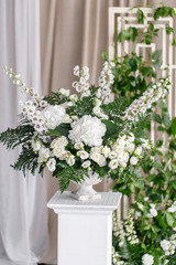Wedding decoration, ceremony in a light tent. Gorgeous bouquet of different flowers. White floral arrangement in vintage vase.