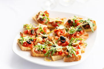 Plate with Italian appetizers. Bruschetta with a cherry tomatoes and shrimps. Parmesan cheese, olives, sun-dried tomatoes and walnuts.