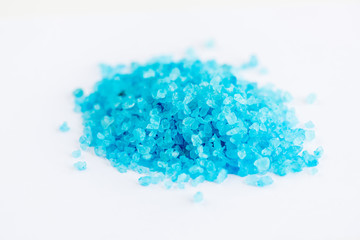 Close up shot of blue crystals isolated on white background, chemical industry concept