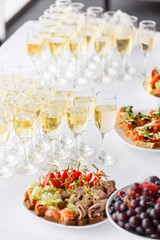 Bartender pouring champagne or wine into wine glasses on the table in restaurant. solemn wedding ceremony or happy new year banquet