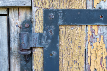 An old hinge mounted in the door. Old carpentry structures.